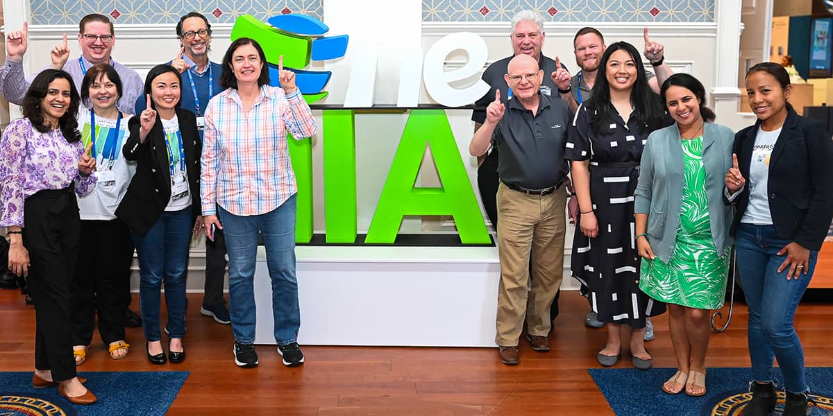 Members posing in front of The IIA logo